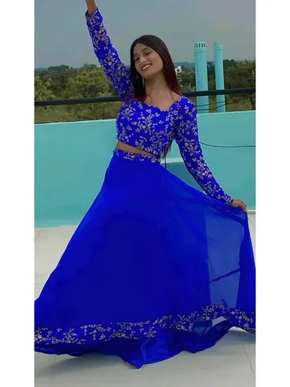A joyful pose in the blue lehenga, showing off its full skirt and beautiful embroidery.