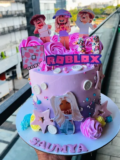 A fun and trendy Roblox themed cake for a gaming fan. This purple cake is decorated with edible character print-outs, stars, and the Roblox logo, perfect for a kid's gaming party.