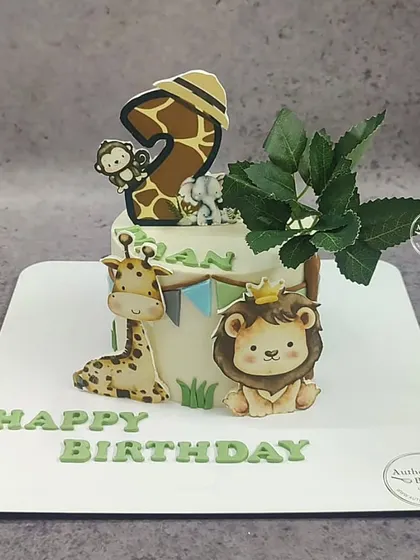 An "Animal in the zoo" cake with a giraffe, lion, and monkey. The number 2 topper is cleverly designed with a giraffe print.