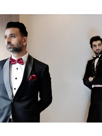 This image captures the essence of our brand's heritage and future. The classic tuxedo with a pop of red from the bow tie and pocket square stands beside a more contemporary embellished piece.