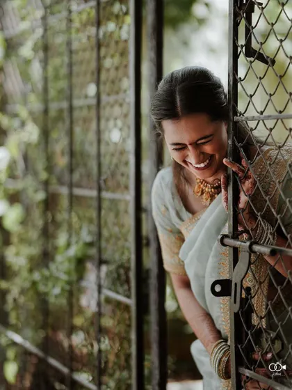 A candid shot of the bride laughing while peeking through an old, rustic gate, her joy infectious.