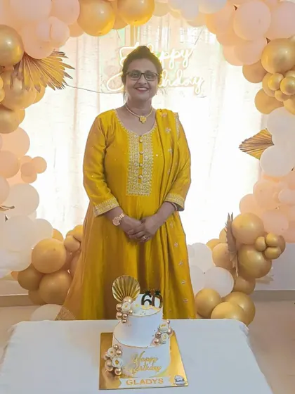 The birthday lady looking radiant as she stands by her elegant 60th birthday cake.