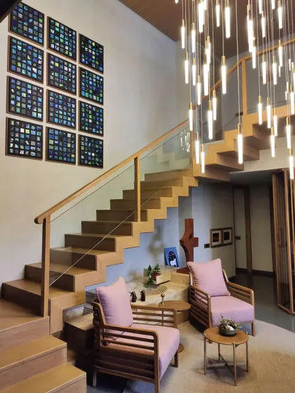 A wider view of the staircase gallery wall, showing how the artwork interacts with the architecture and a cascading light fixture.