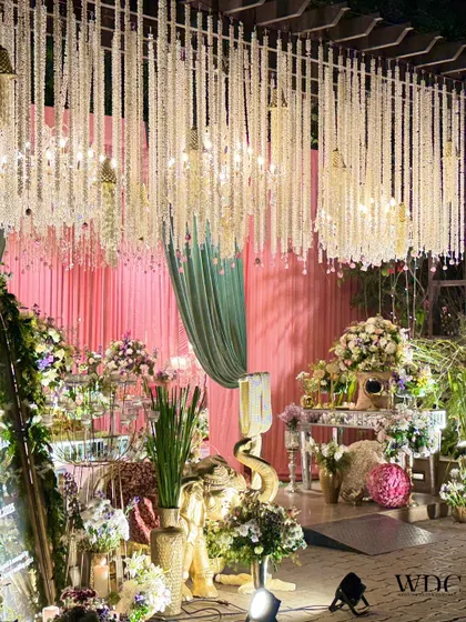A wide view of the reception space, showing the various elements like the hanging floral ceiling, the candle wall, and the elegant guest seating, all coming together to create a grand and serene atmosphere.