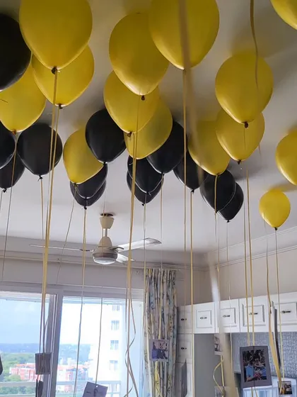 Black and yellow helium balloons with photos attached to the ribbons, a great way to personalize a surprise.