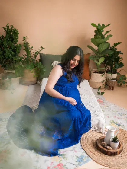 A wider view of our bohemian studio setup, complete with lush greenery and natural textures. This shot captures the peaceful, nesting atmosphere we created for this beautiful maternity session.