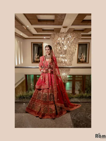 A stunning full-length portrait of the bride in front of a massive crystal chandelier, emphasizing the luxury and grandeur of the wedding venue.