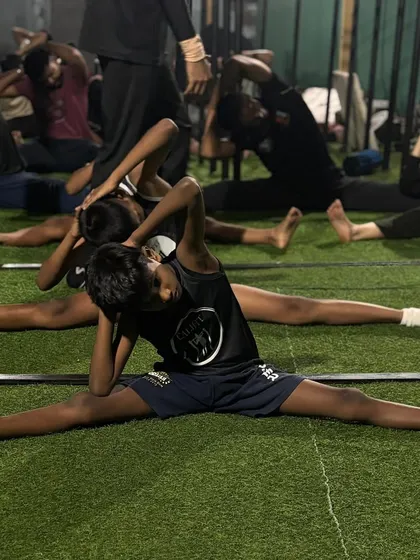 A young athlete working on his middle splits, building a foundation of flexibility that will serve him well in all sports.