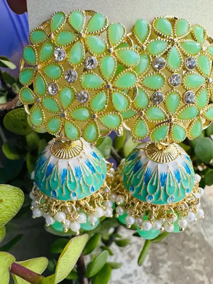 A refreshing mint green pair of jhumkas. The light green floral top and hand-painted dome are perfect for daytime events and summer weddings.
