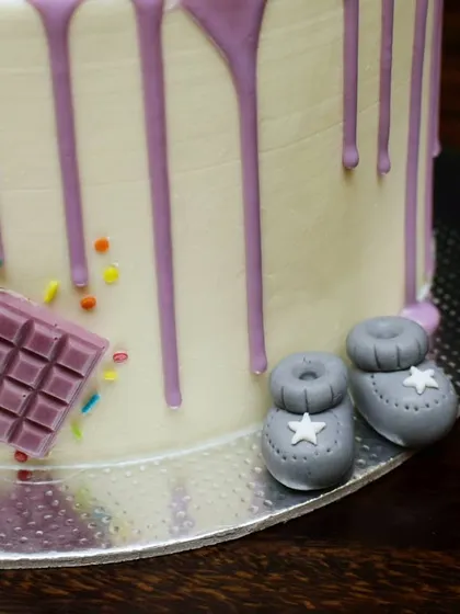 A close-up of the tiny fondant baby booties on the purple drip cake. It's these small, handcrafted details that make a cake extra special.