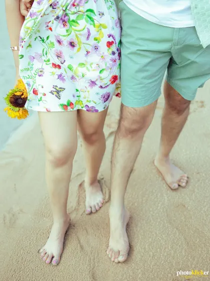 A detail shot of a couple's bare feet in the sand, symbolizing their grounded connection and shared journey.
