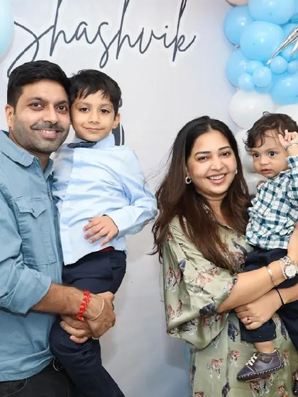 A happy family of four poses together at a birthday celebration.
