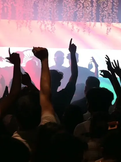 Silhouettes of the crowd with their hands up, vibing to the Indian flag visuals at Masala House.