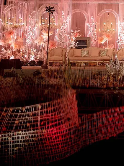A creative shot capturing the reflection of the grand stage on the polished floor. The glowing pink and red hues create a dramatic, fiery effect, showcasing the dynamic lighting design of the event.