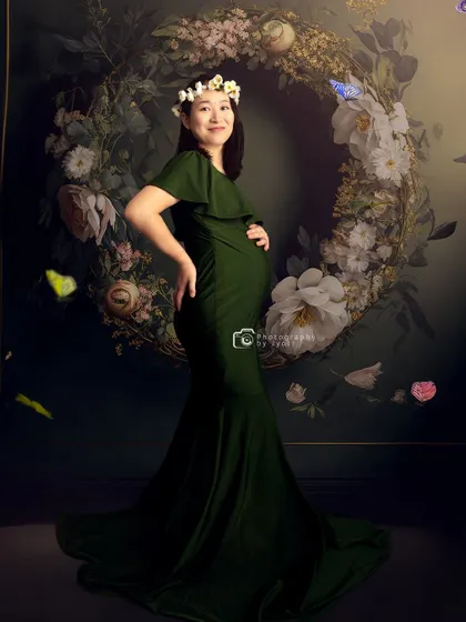 A joyful portrait with a mom-to-be wearing a floral crown against a large floral wreath, creating a bohemian and natural feel.
