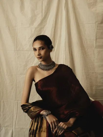 An elegant and minimalist portrait. The simple background and lighting keep the focus on the model and the beautiful drape of the saree.