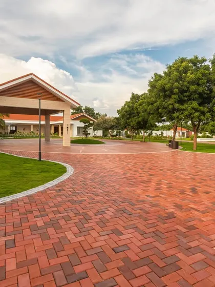 A view of the curved driveway and entrance portico, showcasing the scale of the property and the careful integration of hardscaping and softscaping to create a harmonious journey through the site.