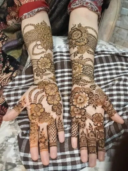 A lovely shot of a full-coverage floral mehendi design, featuring delicate hanging chains and bell motifs on the wrist.