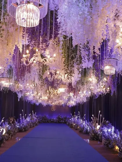 The reception pathway was a lavish corridor of hanging wisteria and crystal chandeliers. The deep blue carpet and ambient lighting created a sense of walking through a magical, starlit forest.