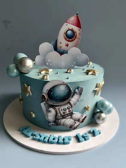 3, 2, 1, blast off! An out-of-this-world space-themed cake for a first birthday, featuring a friendly astronaut, a rocket ship soaring through clouds, and a galaxy of edible stars.