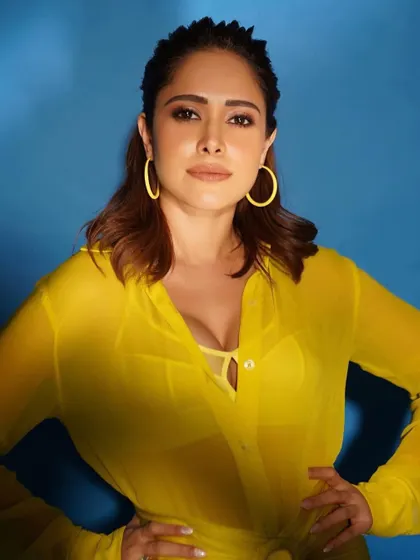 A close-up of the sheer yellow shirt and matching earrings. It's a look that's all about confidence.