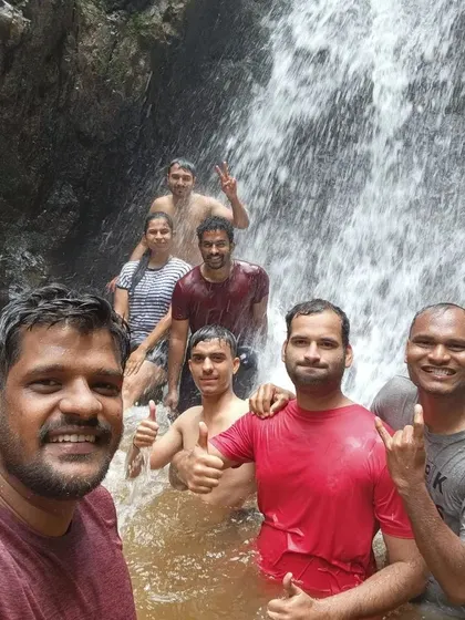 A team selfie in front of a waterfall on the Netravati Peak trek. Cooling off in the natural pools is a highlight of the journey.