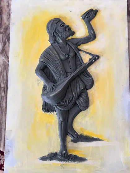 The mural after the sculpting is complete and the first layer of paint has been applied. The yellow background brings a divine glow, and the grey base coat prepares the figure for its final, detailed colors.