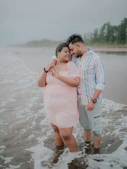 A romantic pre-wedding photo of a couple standing in the gentle waves of the sea.