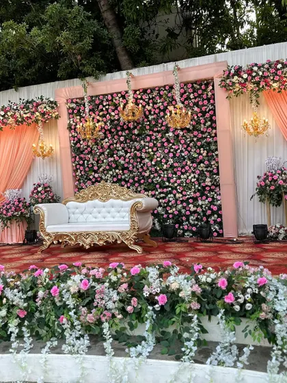 The full stage setup, showing the balance between the floral backdrop, the elegant furniture, and the soft drapery.