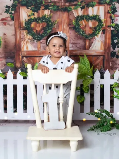 This little one is peeking over a chair, celebrating her first birthday with some panda friends.