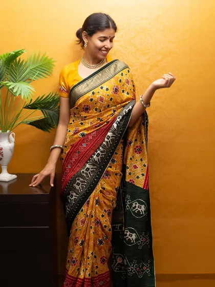 Modeling a traditional yellow Patola silk saree, this shot shows the full drape and rich pattern, perfect for festive or heritage collections.