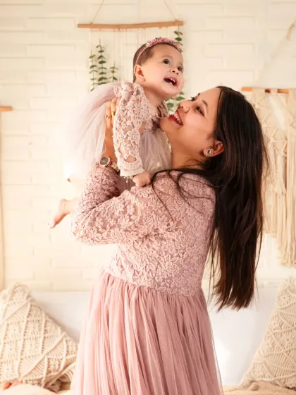 A mother lifts her daughter in a moment of pure happiness during their family photoshoot.