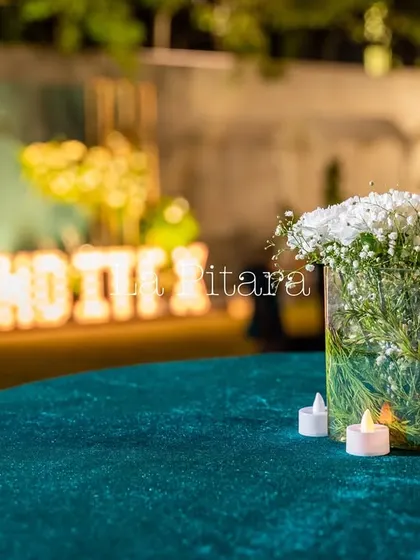 A simple glass vase with baby's breath on a cocktail table, with the lit-up "INDITEX" letters glowing in the background. Even the smallest details contribute to the overall polished feel of a corporate event.