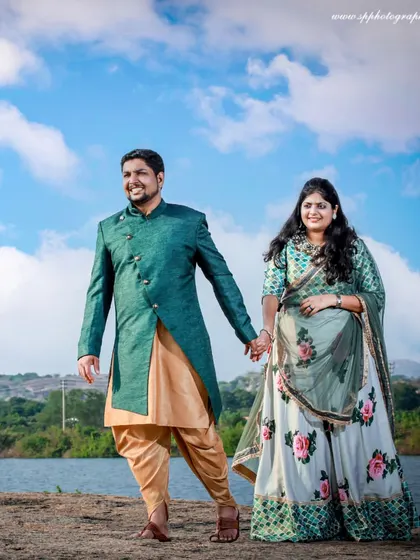 An outdoor pre-wedding shoot by the water. The scenic landscape and open sky provide a stunning, expansive backdrop for a classic romantic portrait.