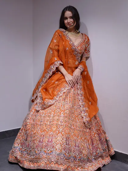 Vibrant hues, exquisite threads! A full view of the heavily embroidered orange bridal lehenga, a perfect blend of drama and elegance for your special day.