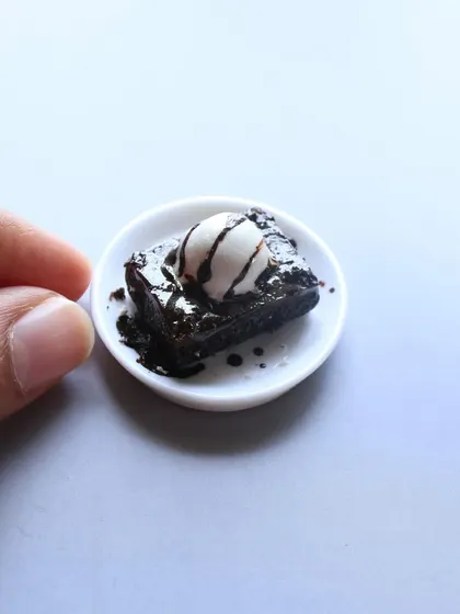 A tiny brownie with a scoop of vanilla ice cream and chocolate sauce.