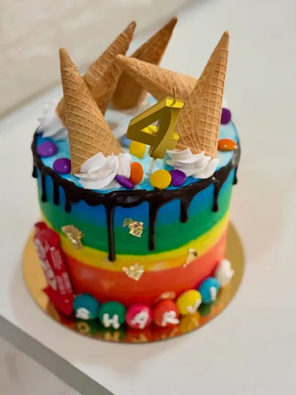A different angle of the fun rainbow and ice cream cone cake, showing the personalized name at the base.