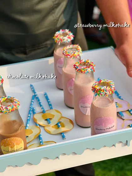 Strawberry and chocolate milkshakes with rainbow sprinkle rims, served with fun paper straws for the little guests.