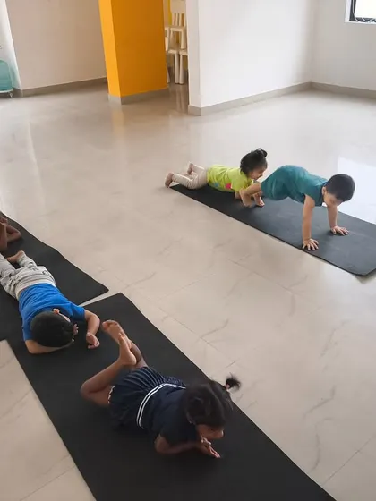 Students practice a plank-like pose on their mats. This exercise is excellent for building core strength, which is fundamental for all physical activities.