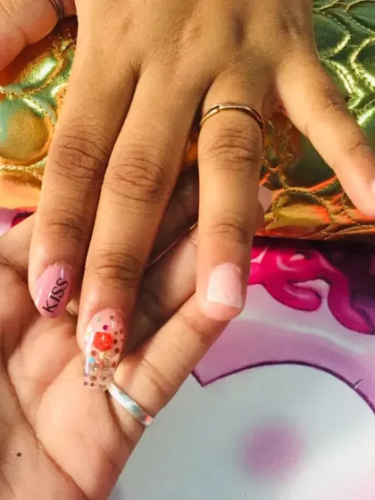 Here I am demonstrating a design for a student. This shows how we work together on techniques like lettering and encapsulation, with a clear nail featuring red heart glitter and the word 'Kiss'.