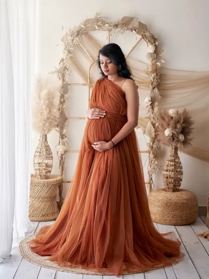 Embrace a natural, earthy vibe with our Copper gown. This look is perfect for our boho-themed studio setups, featuring pampas grass and wicker furniture for a warm and serene maternity session.