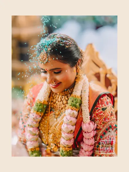 A beautiful candid of the bride during the Akshataropanam ritual, where rice grains are showered as blessings. Her joyful smile perfectly captures the spirit of the moment.
