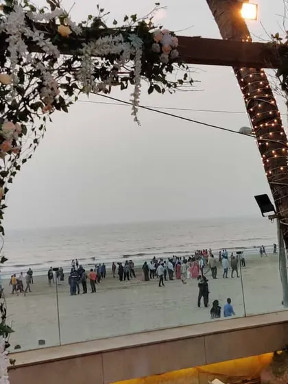 A rustic wooden arch decorated with white flowers and greenery, perfectly framing the view of the beach. This element served as a beautiful entrance piece for a Christian wedding ceremony.