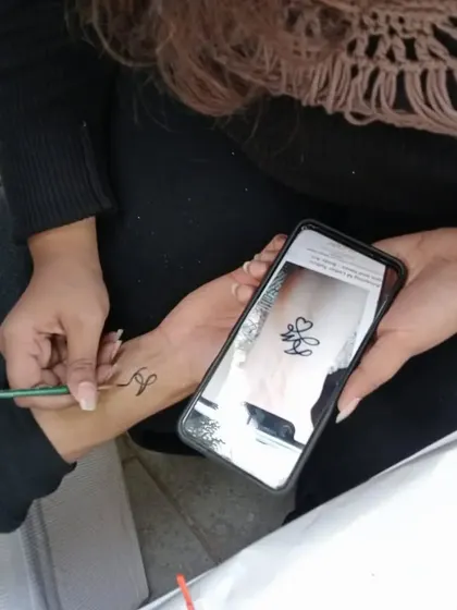 Sometimes clients have a specific design in mind. Here, I'm using a photo on a phone as a reference to create a custom initial tattoo.