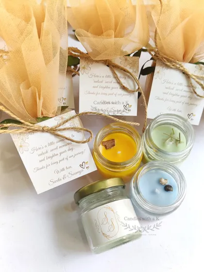 The packaged wedding favors, showing the mini candles wrapped in beige net with custom thank you cards.