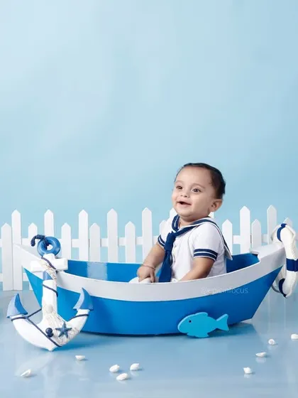 A happy little sailor in our nautical-themed setup. The crisp blue and white colors, along with props like a ship's wheel and lighthouse, create a classic maritime feel.