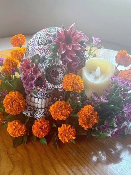 A beautifully painted sugar skull centerpiece, surrounded by marigolds, perfect for a Day of the Dead or Halloween theme.