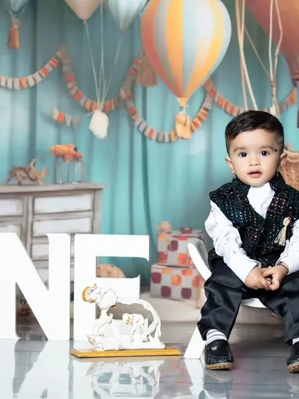 This little boy is looking sharp for his first birthday photo in a stylish vest and trousers.