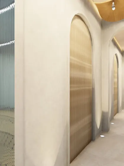 A detail of the corridor's textures, showing the interplay between the smooth, lime-washed walls and the reeded texture of the arched doorways. The floor-level lighting adds another layer of warmth and guidance.
