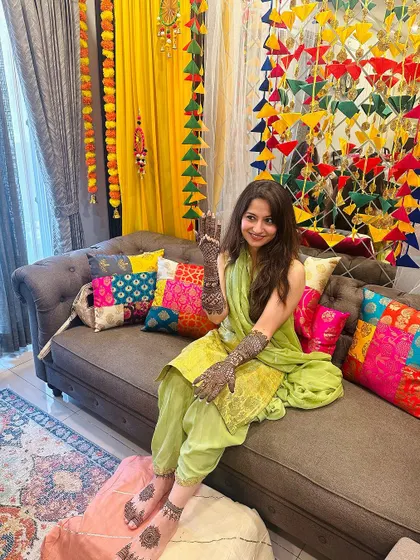 A bride relaxing on the couch in a colorful setting after her mehndi application.